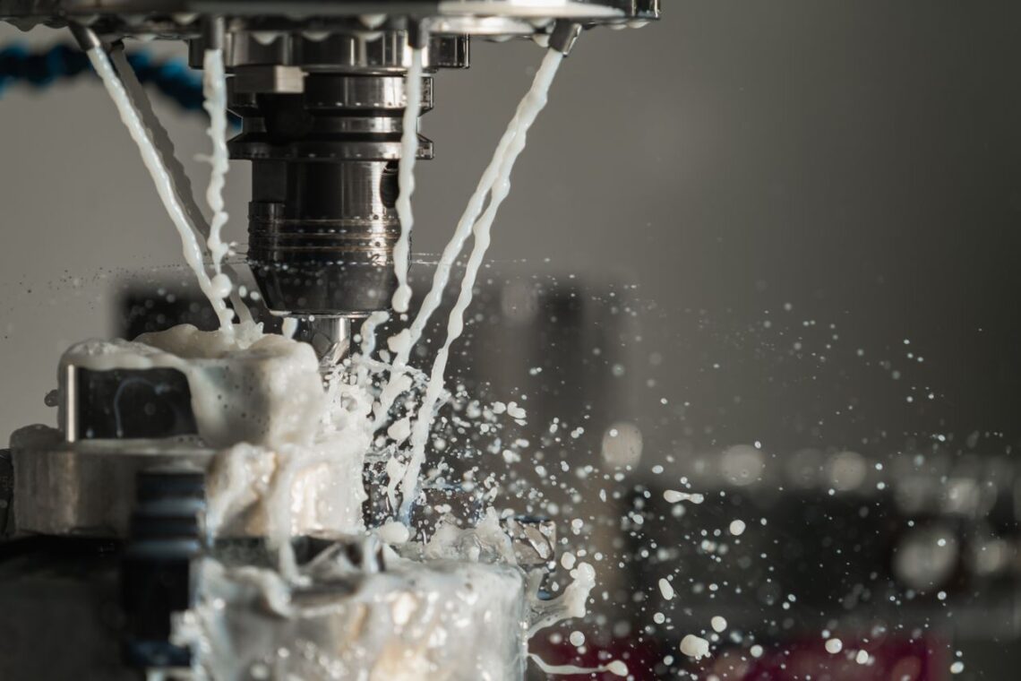 Dynamic close-up of CNC machine with coolant splashing during metalwork operation.
