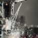 Dynamic close-up of CNC machine with coolant splashing during metalwork operation.